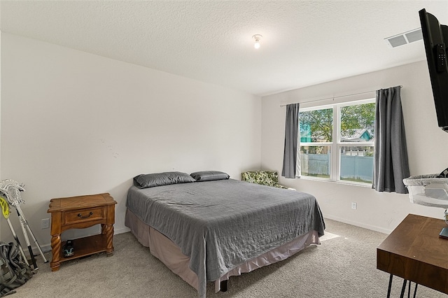 bedroom featuring light carpet and a textured ceiling