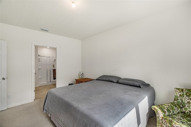 carpeted bedroom featuring ensuite bathroom and a textured ceiling