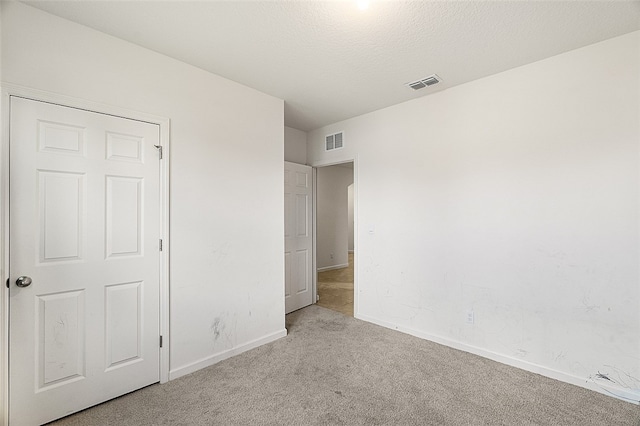 unfurnished bedroom featuring light carpet, a closet, and a textured ceiling