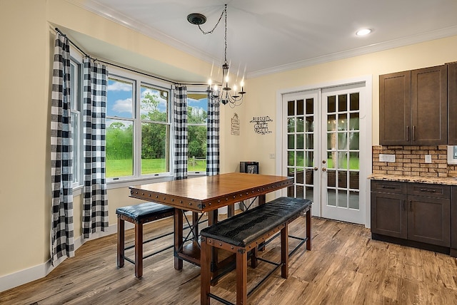 dining space with a chandelier, light hardwood / wood-style flooring, french doors, and ornamental molding