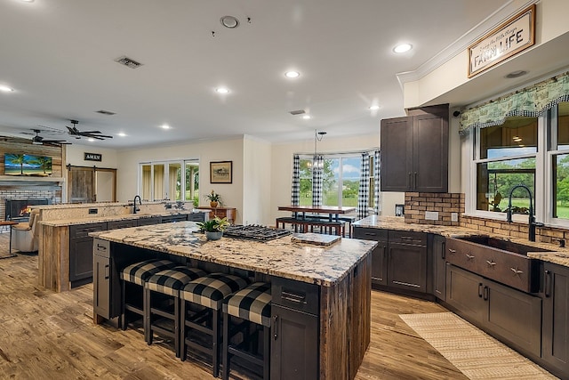 kitchen featuring light stone counters, a center island, sink, a breakfast bar, and light hardwood / wood-style flooring