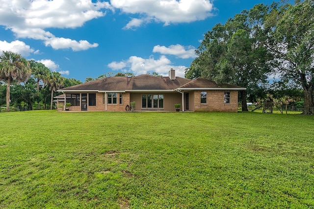 back of house featuring a playground and a yard