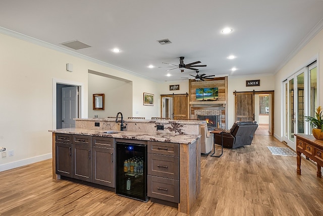 kitchen with light stone counters, light wood-type flooring, a barn door, sink, and beverage cooler