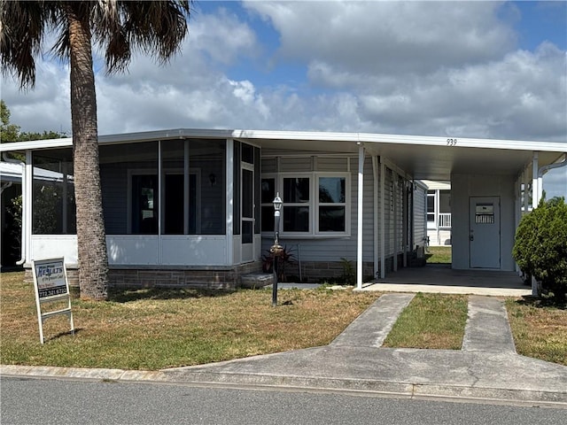 939 Laurel Cir, Barefoot Bay, FL 32976 - manufactured / mobile home with a sunroom, an attached carport, and a front yard