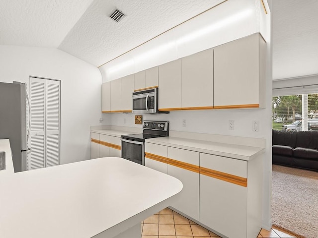 321 Browning Ter, Sebastian, FL 32958 - kitchen featuring appliances with stainless steel finishes, light tile patterned floors, a textured ceiling, light countertops, and vaulted ceiling