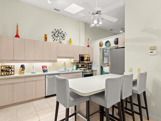 636 Centre Ct SW Unit 102, Vero Beach, FL 32962 - kitchen with appliances with stainless steel finishes, a sink, light brown cabinets, a kitchen bar, and high vaulted ceiling