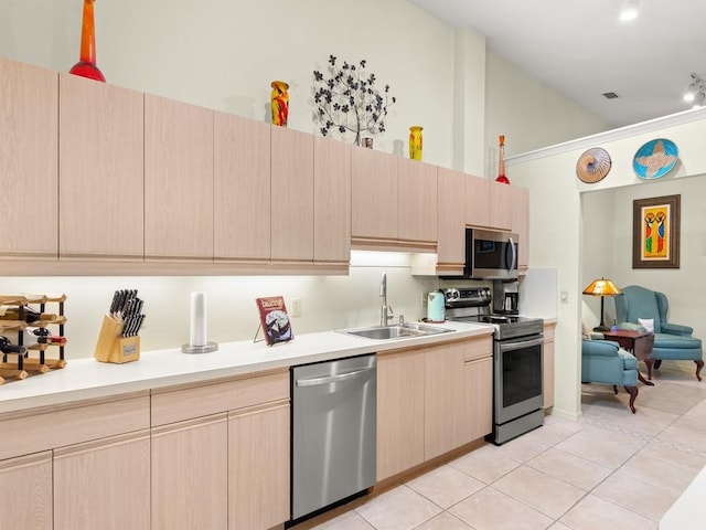 636 Centre Ct SW Unit 102, Vero Beach, FL 32962 - kitchen featuring appliances with stainless steel finishes, light brown cabinetry, a sink, light tile patterned floors, and high vaulted ceiling