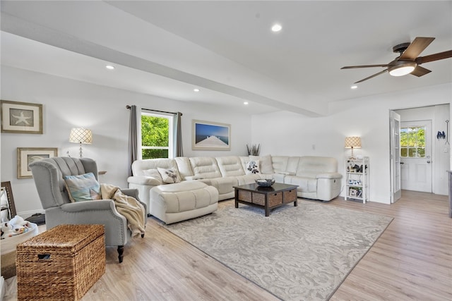 living room with beamed ceiling, ceiling fan, and light wood-type flooring