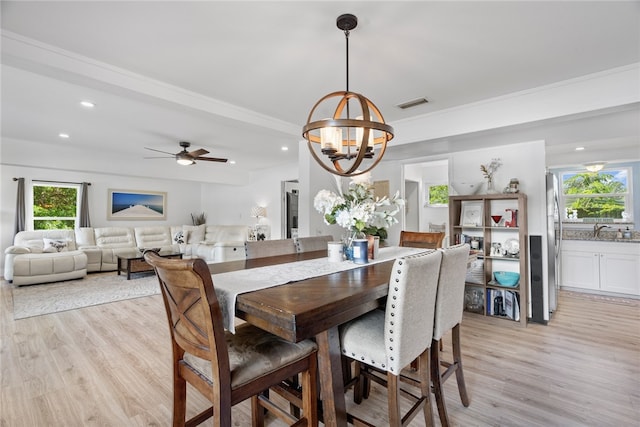 dining space with ceiling fan with notable chandelier, ornamental molding, and light hardwood / wood-style flooring