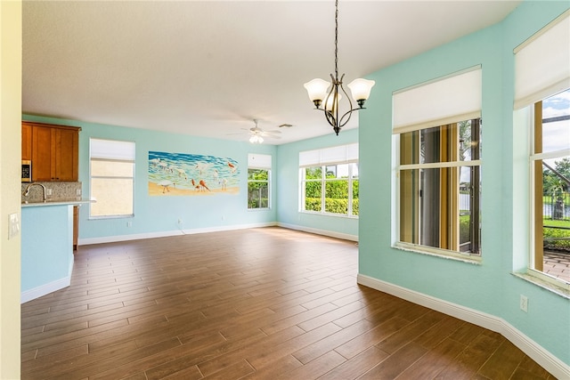 unfurnished living room with ceiling fan with notable chandelier, dark hardwood / wood-style floors, and sink