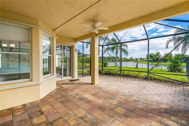 view of patio with ceiling fan, a lanai, and a water view