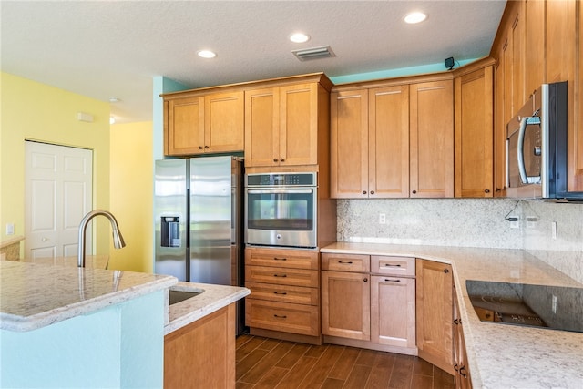 kitchen featuring light stone countertops, stainless steel appliances, tasteful backsplash, dark hardwood / wood-style floors, and a textured ceiling