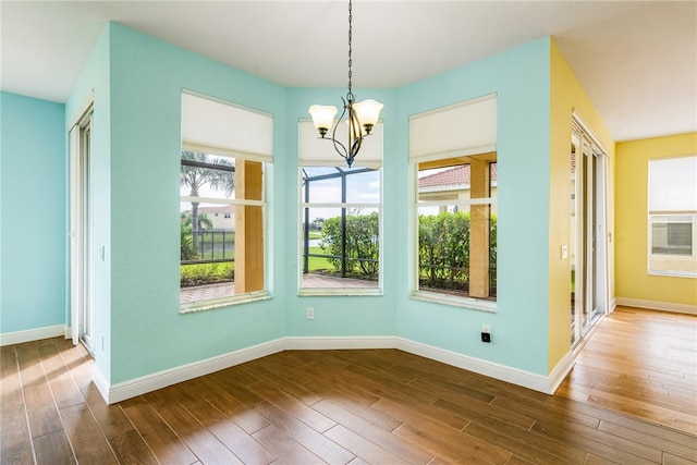 unfurnished dining area featuring a chandelier, hardwood / wood-style flooring, and plenty of natural light