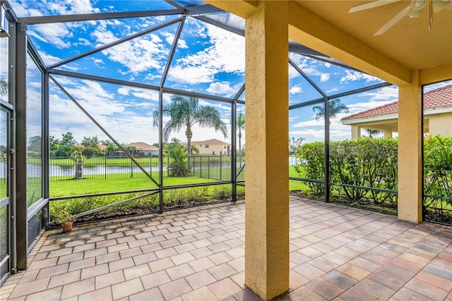 unfurnished sunroom featuring ceiling fan and a water view