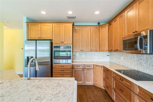 kitchen featuring decorative backsplash, light stone countertops, dark wood-type flooring, and appliances with stainless steel finishes