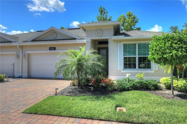 6005 Bella Rosa Ln, Vero Beach, FL 32966 - view of front facade featuring an attached garage, decorative driveway, stucco siding, and a front lawn