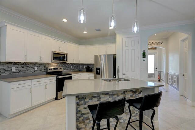 6005 Bella Rosa Ln, Vero Beach, FL 32966 - kitchen with appliances with stainless steel finishes, a sink, arched walkways, backsplash, and white cabinetry