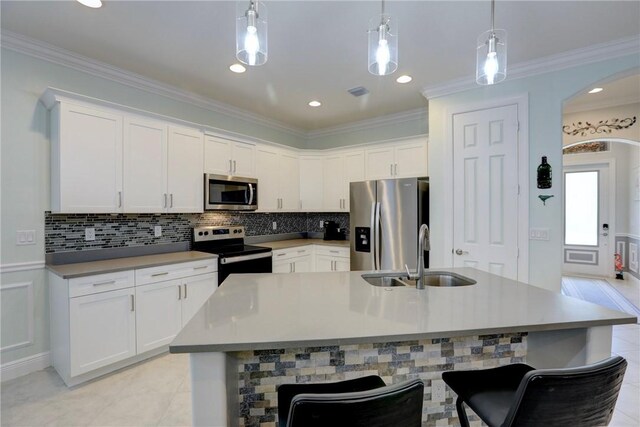 6005 Bella Rosa Ln, Vero Beach, FL 32966 - kitchen featuring appliances with stainless steel finishes, a sink, arched walkways, white cabinetry, and crown molding
