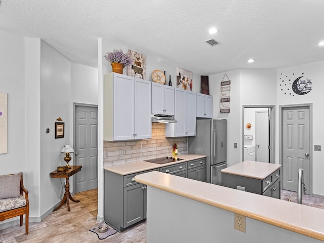 kitchen featuring light wood-type flooring, a kitchen island, gray cabinetry, and stainless steel fridge