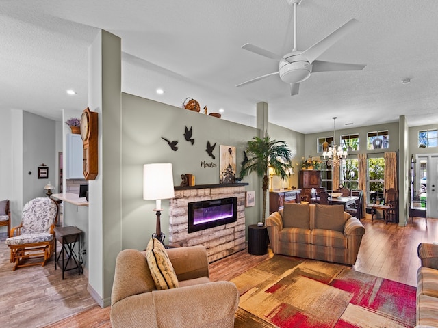 living room with light wood-type flooring, ceiling fan with notable chandelier, and a textured ceiling