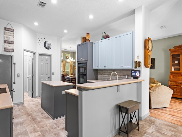 kitchen with a center island, an inviting chandelier, decorative backsplash, hanging light fixtures, and double oven