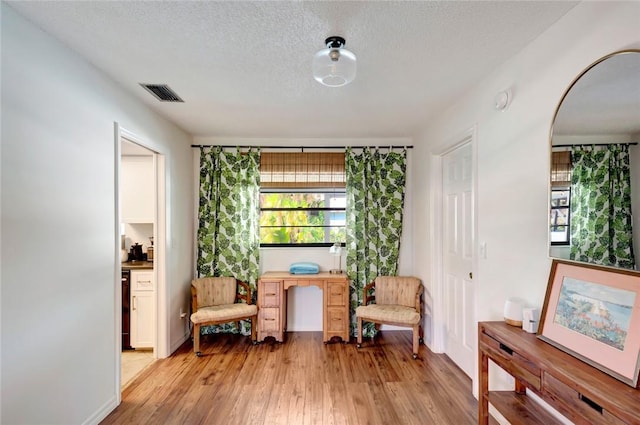 living area with a textured ceiling and light hardwood / wood-style floors