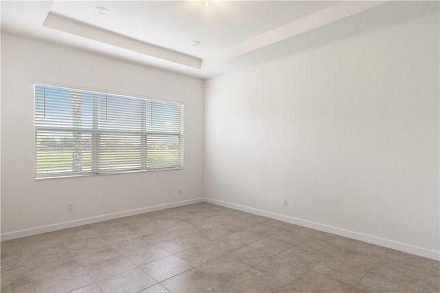 unfurnished room featuring a tray ceiling and light tile patterned flooring