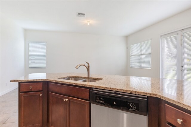 kitchen with light tile patterned floors, sink, light stone counters, and dishwasher