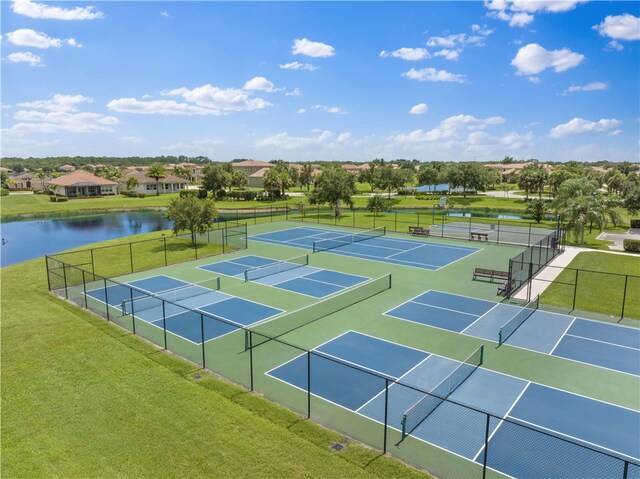 view of tennis court with a water view and a yard