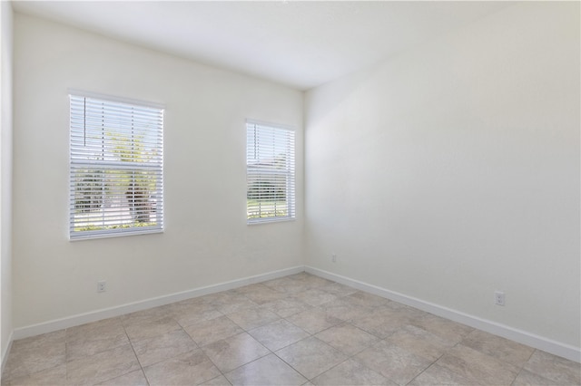 empty room featuring light tile patterned flooring and a healthy amount of sunlight