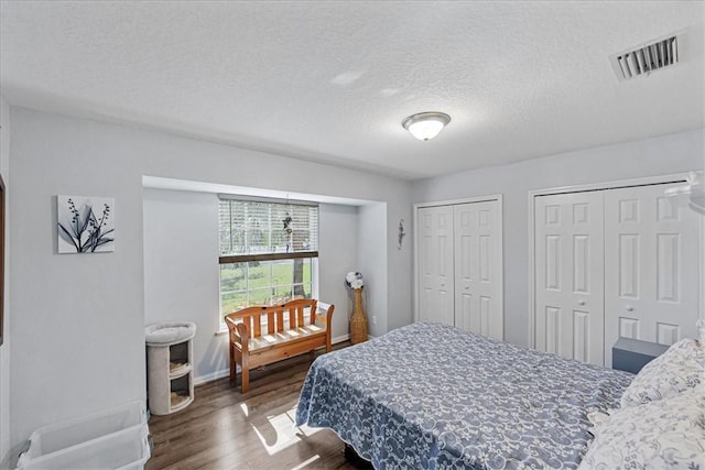 bedroom featuring multiple closets, dark wood-type flooring, and a textured ceiling