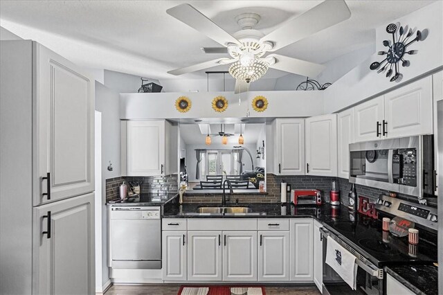 kitchen with appliances with stainless steel finishes, vaulted ceiling, ceiling fan, sink, and white cabinetry