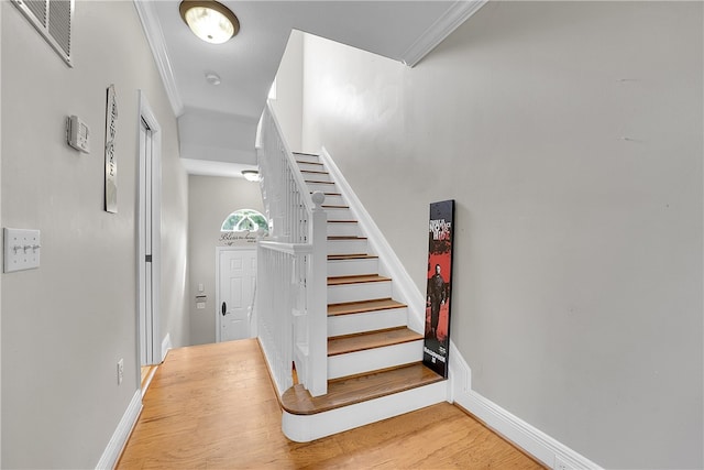 stairs with hardwood / wood-style flooring and crown molding