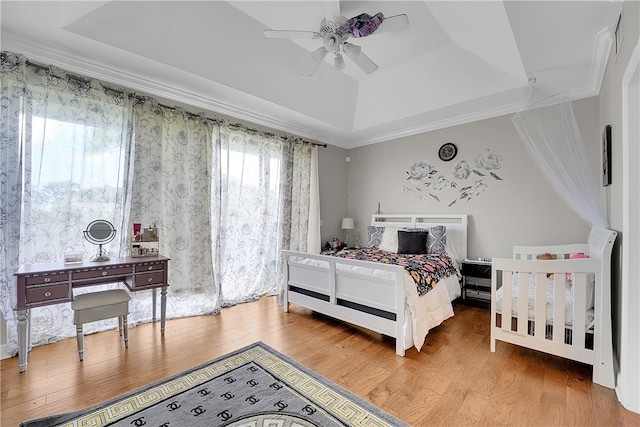 bedroom featuring light hardwood / wood-style floors, ceiling fan, and a tray ceiling