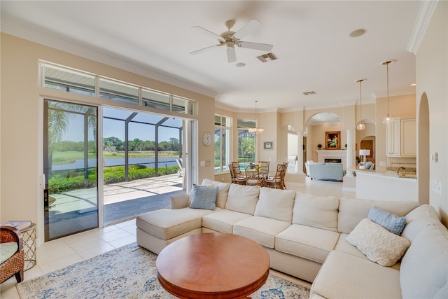 tiled living room featuring a water view, ornamental molding, and ceiling fan with notable chandelier