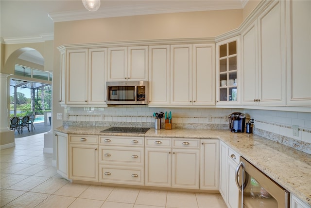 kitchen with black electric cooktop, cream cabinetry, beverage cooler, and tasteful backsplash