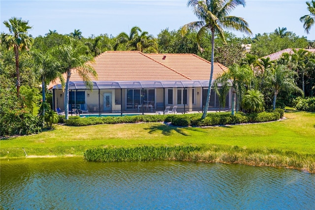 rear view of house featuring a lanai, a water view, and a yard