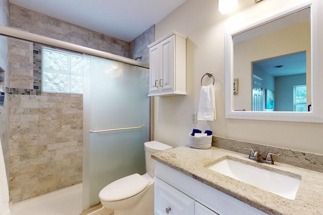 bathroom with vanity, a shower with door, and toilet