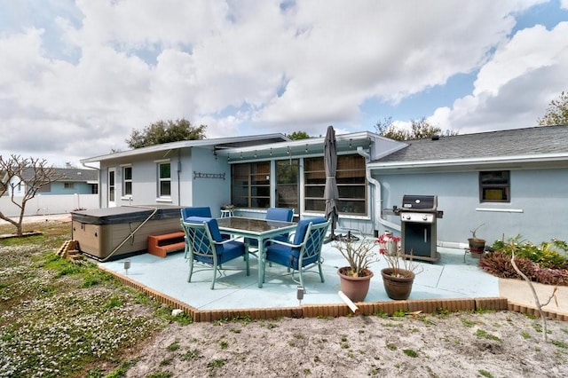 back of property featuring a hot tub and a patio area