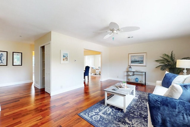 living room featuring ceiling fan and dark hardwood / wood-style floors