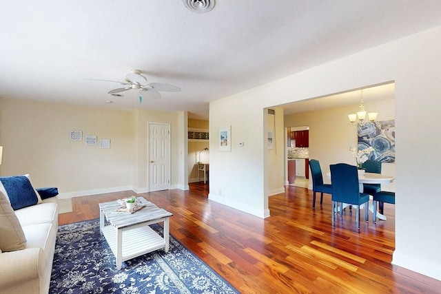 living room featuring ceiling fan with notable chandelier and wood-type flooring