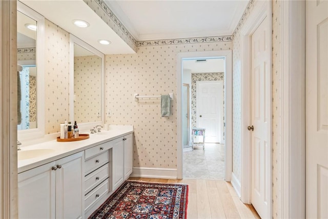 1250 W Southwinds Blvd Unit 310, Vero Beach, FL 32963 - bathroom with wallpapered walls, double vanity, wood finished floors, and crown molding