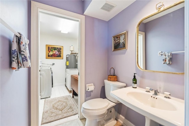 1250 W Southwinds Blvd Unit 310, Vero Beach, FL 32963 - bathroom featuring washing machine and clothes dryer, water heater, and tile patterned flooring
