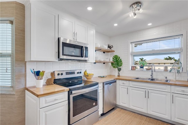 540 Grove Isle Cir Unit 207, Vero Beach, FL 32962 - kitchen featuring appliances with stainless steel finishes, a sink, wood counters, white cabinetry, and healthy amount of natural light