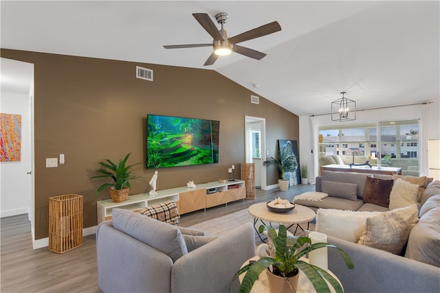 living room featuring lofted ceiling, light wood-type flooring, and ceiling fan with notable chandelier