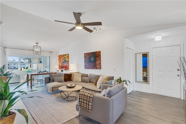 living room featuring ceiling fan with notable chandelier, light hardwood / wood-style floors, and lofted ceiling