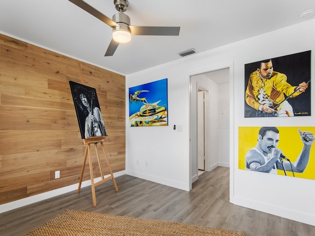 interior space with wooden walls, ceiling fan, and hardwood / wood-style flooring