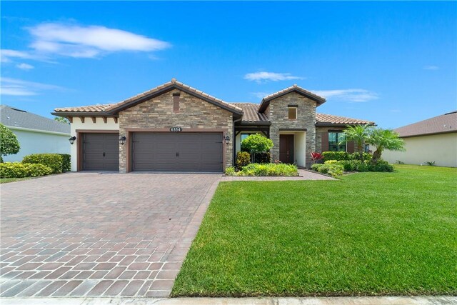 6354 Arcadia Sq, Vero Beach, FL 32966 - mediterranean / spanish house with stone siding, a tile roof, a front lawn, a garage, and decorative driveway