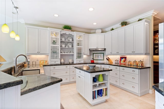 kitchen with dark stone counters, white cabinetry, sink, and a center island