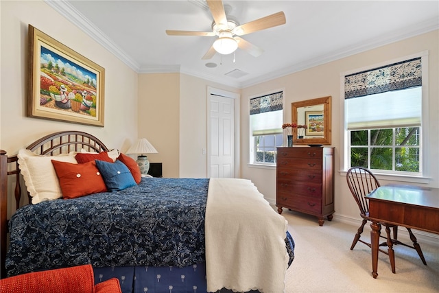 carpeted bedroom with ceiling fan, a closet, and crown molding